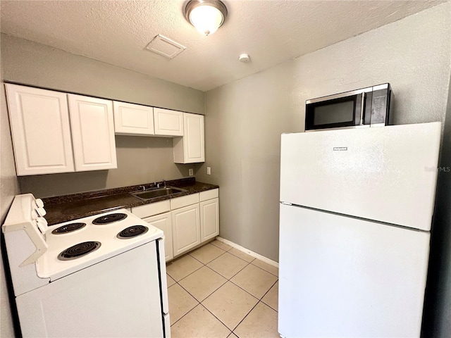 kitchen with white appliances, white cabinets, sink, light tile patterned floors, and a textured ceiling