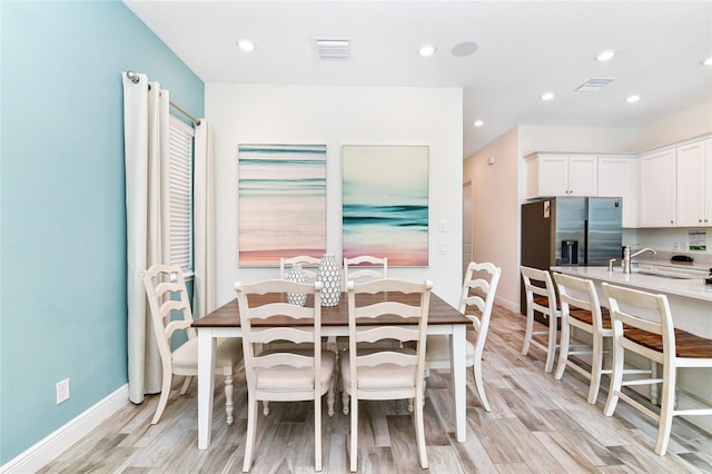 dining space with sink and light hardwood / wood-style floors