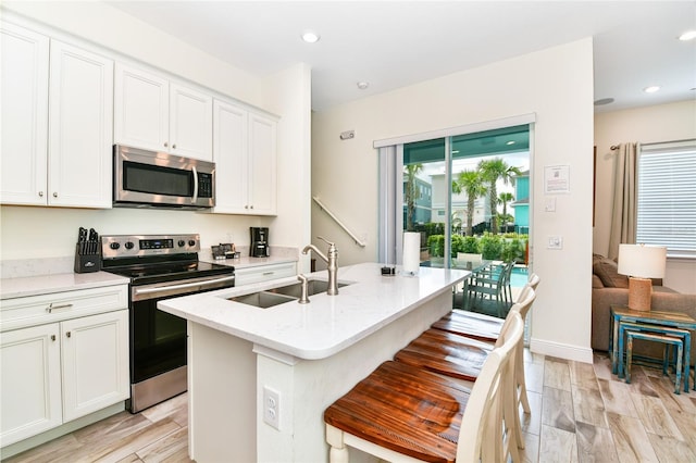 kitchen with white cabinetry, sink, a center island with sink, and appliances with stainless steel finishes