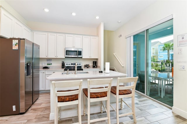 kitchen with white cabinets, an island with sink, and appliances with stainless steel finishes