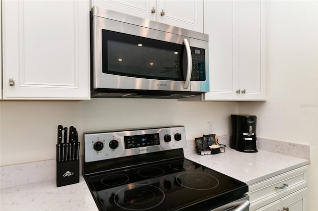 kitchen featuring white cabinetry, light stone counters, and stainless steel appliances