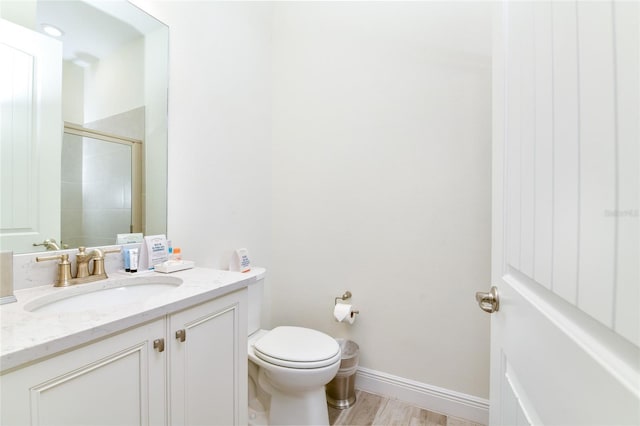 bathroom featuring hardwood / wood-style floors, vanity, toilet, and an enclosed shower