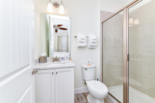 bathroom featuring vanity, hardwood / wood-style flooring, ceiling fan, toilet, and an enclosed shower