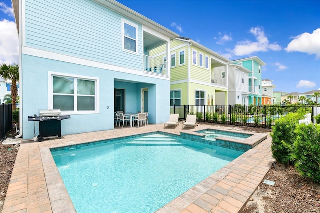 back of property with a patio area, a swimming pool with hot tub, and a balcony