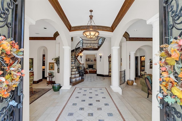 foyer featuring decorative columns, ornamental molding, and a notable chandelier