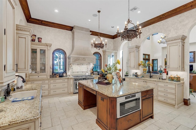 kitchen featuring a center island, hanging light fixtures, high end stove, cream cabinetry, and custom exhaust hood