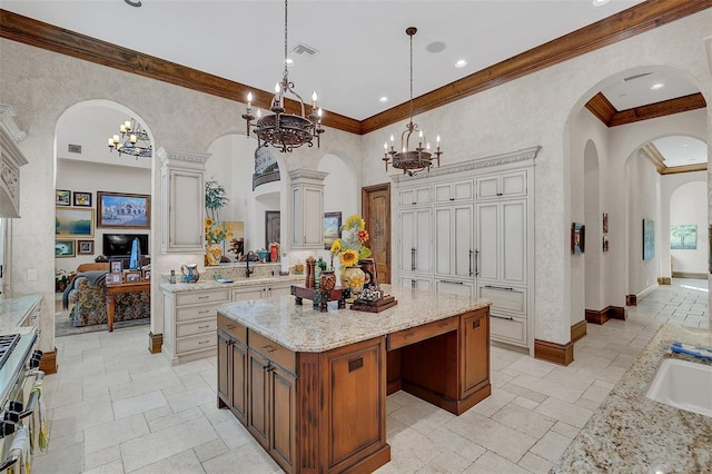 kitchen with sink, a center island, decorative columns, pendant lighting, and stainless steel range with gas stovetop