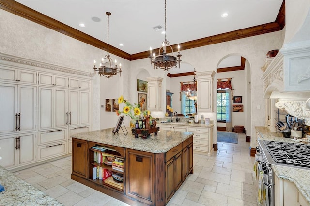 kitchen with sink, high end stove, decorative light fixtures, a kitchen island, and decorative columns