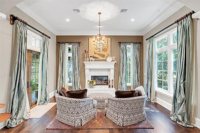 living area featuring crown molding, dark wood-type flooring, and an inviting chandelier