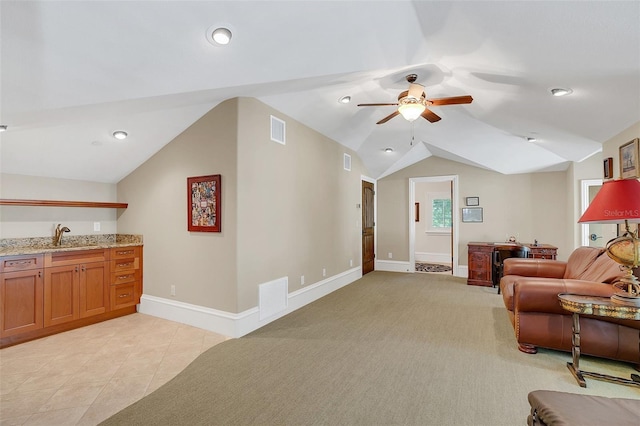 tiled living room featuring ceiling fan, lofted ceiling, and sink