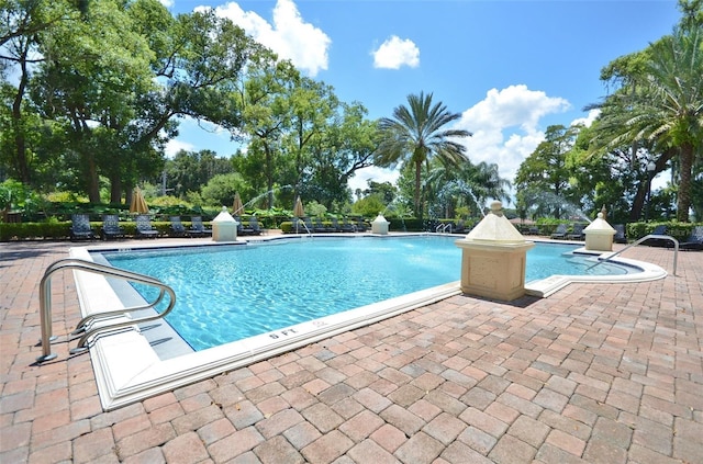 view of swimming pool with pool water feature and a patio area