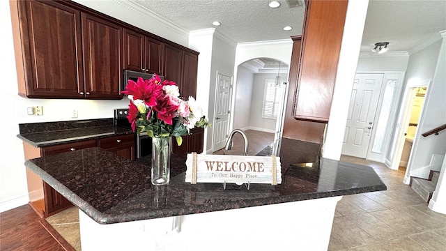 kitchen featuring a breakfast bar, light tile patterned floors, a textured ceiling, and ornamental molding