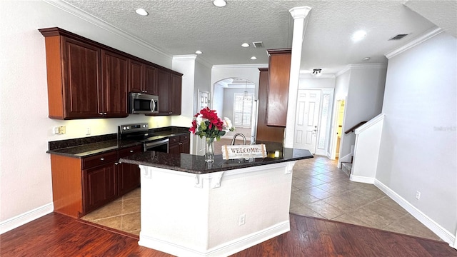 kitchen featuring a breakfast bar, dark tile patterned floors, a textured ceiling, and appliances with stainless steel finishes