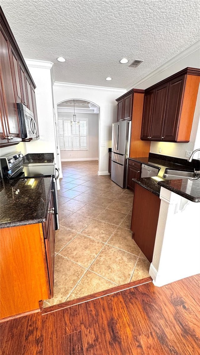 kitchen with a textured ceiling, crown molding, sink, and stainless steel appliances