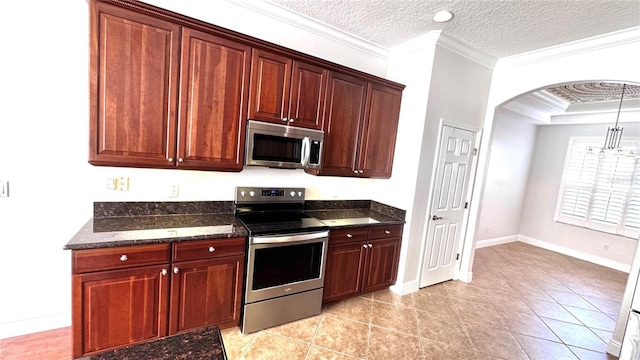 kitchen featuring dark stone counters, a textured ceiling, stainless steel appliances, crown molding, and light tile patterned flooring