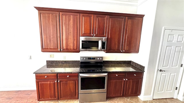 kitchen with appliances with stainless steel finishes, light tile patterned floors, crown molding, and dark stone countertops