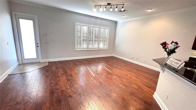 unfurnished dining area featuring wood-type flooring, a textured ceiling, track lighting, and ornamental molding