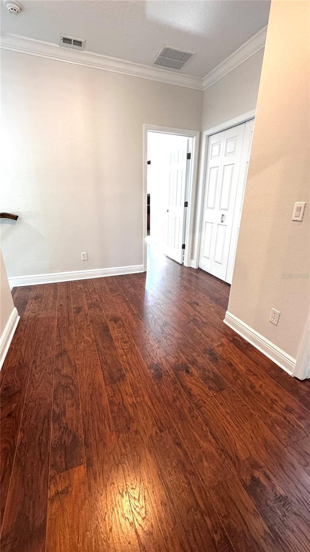 spare room featuring dark hardwood / wood-style floors and crown molding