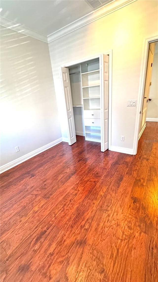 unfurnished bedroom with dark hardwood / wood-style floors, a closet, and ornamental molding