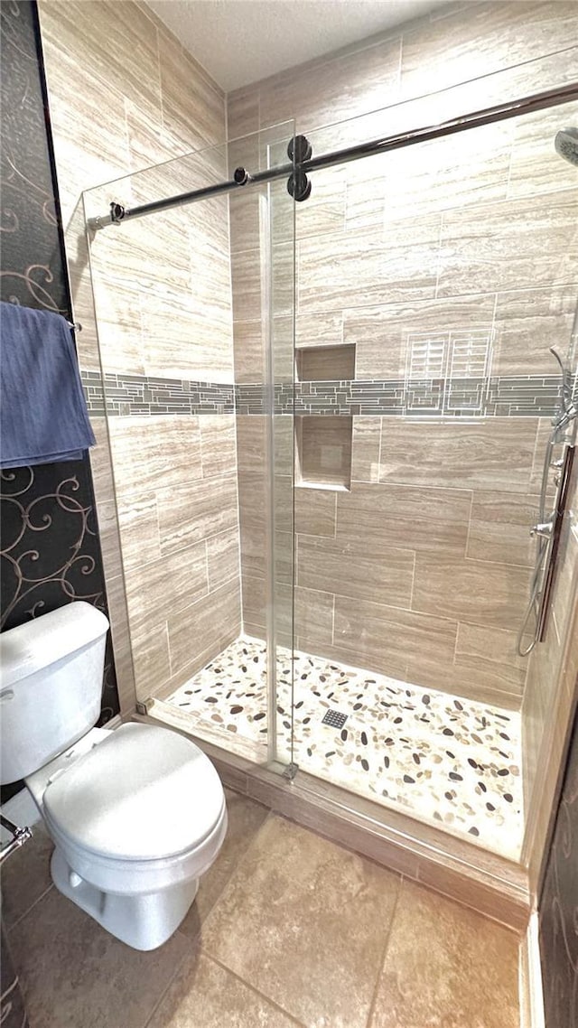 bathroom featuring a tile shower and toilet