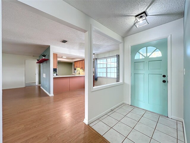 entryway with light tile patterned floors and a textured ceiling