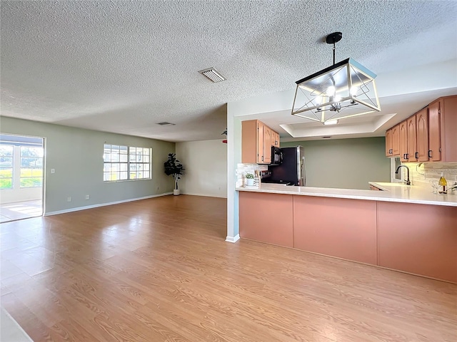 kitchen with decorative light fixtures, light hardwood / wood-style floors, kitchen peninsula, and tasteful backsplash