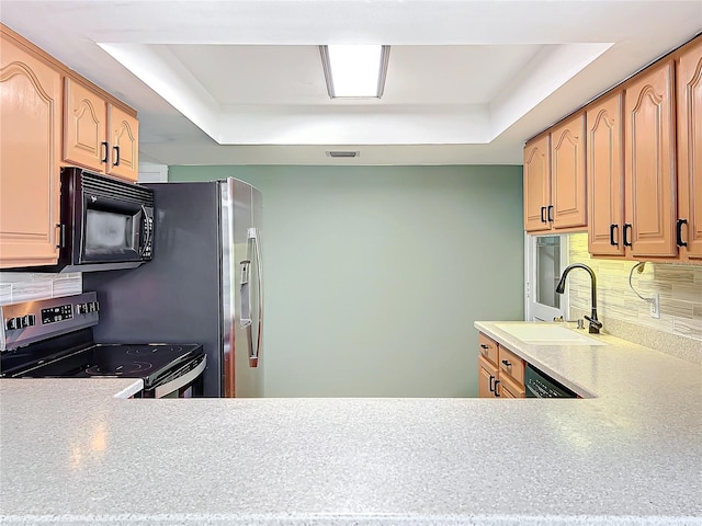 kitchen with a tray ceiling, decorative backsplash, sink, and black appliances