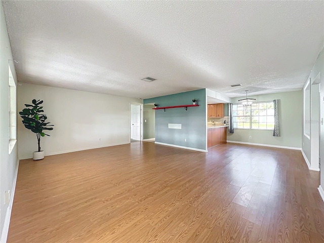 unfurnished living room with light hardwood / wood-style floors and a textured ceiling