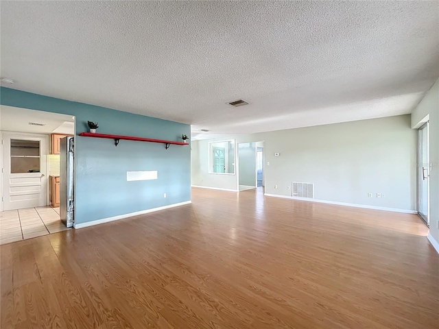 spare room featuring a textured ceiling and light hardwood / wood-style floors