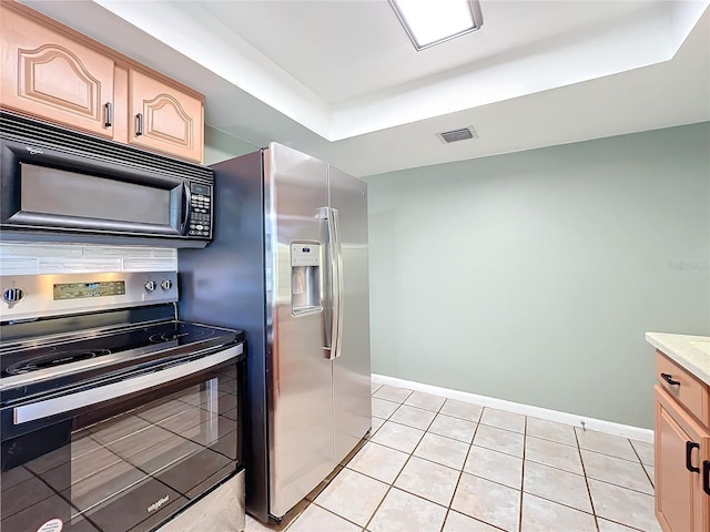 kitchen with light tile patterned floors, light brown cabinets, stainless steel appliances, and a raised ceiling