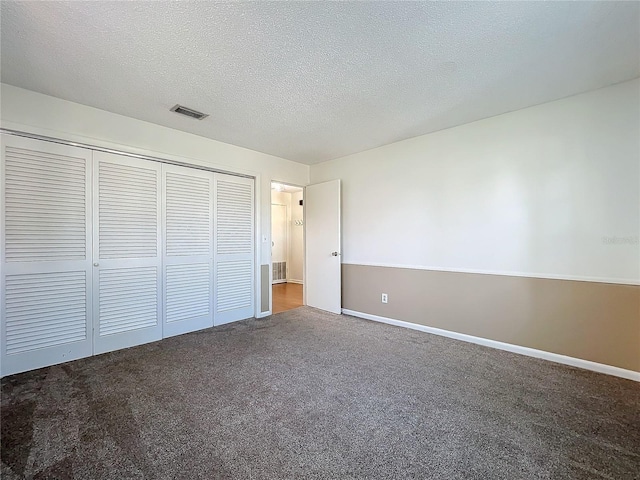 unfurnished bedroom featuring carpet, a textured ceiling, and a closet