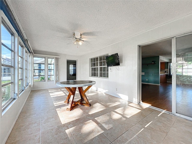 unfurnished sunroom with ceiling fan