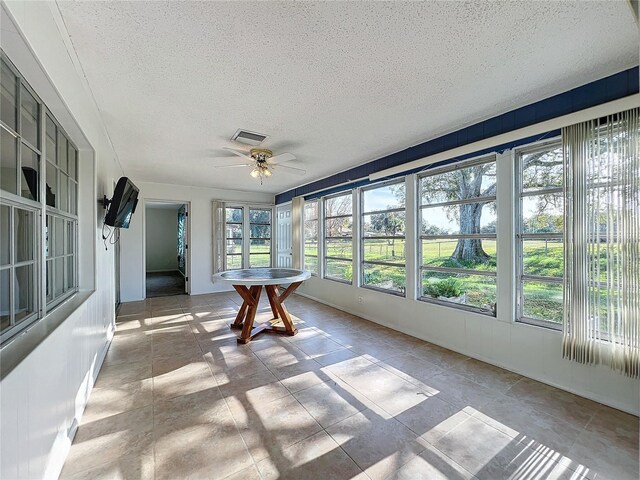 unfurnished sunroom with ceiling fan