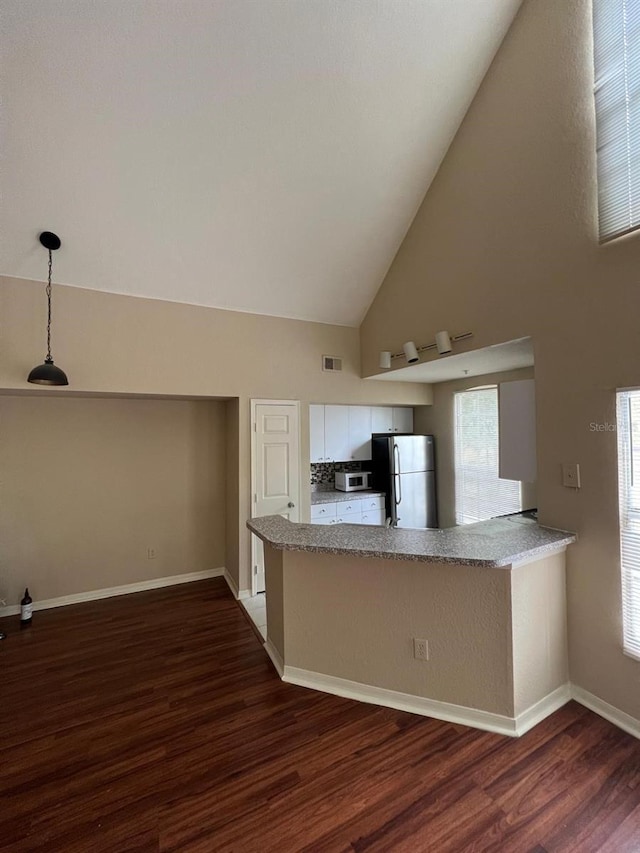 kitchen with pendant lighting, kitchen peninsula, stainless steel fridge, dark hardwood / wood-style flooring, and white cabinetry