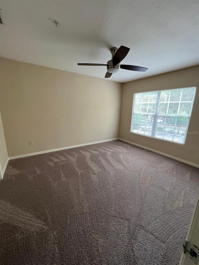 carpeted spare room featuring ceiling fan and a textured ceiling