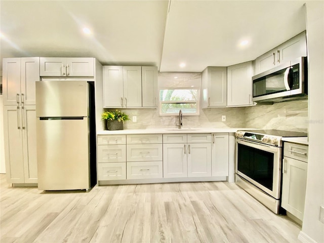 kitchen with decorative backsplash, sink, stainless steel appliances, and light wood-type flooring