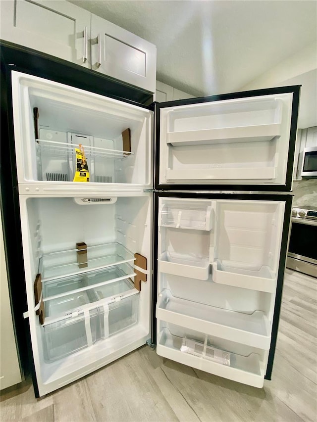 details with light hardwood / wood-style floors, white cabinetry, and appliances with stainless steel finishes