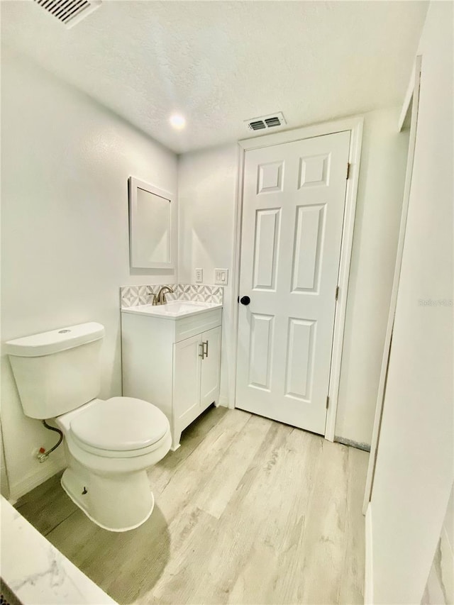 bathroom featuring hardwood / wood-style floors, vanity, a textured ceiling, and toilet