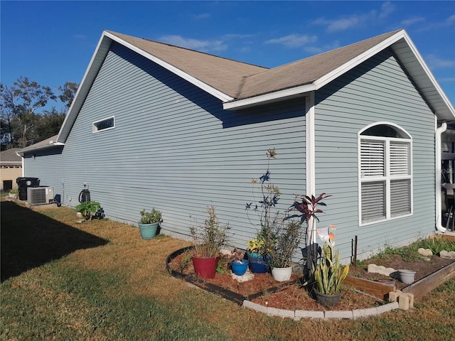 view of side of home with central AC unit and a lawn