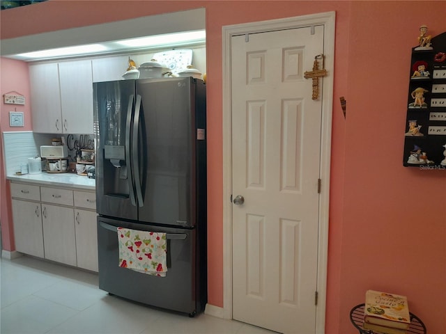 kitchen featuring light tile patterned floors, stainless steel fridge with ice dispenser, and white cabinetry