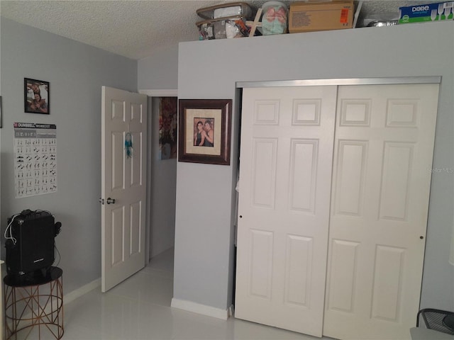 bedroom with a textured ceiling, light tile patterned floors, and a closet