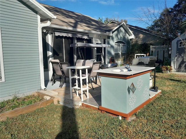 wooden deck featuring exterior bar, a patio area, and a lawn