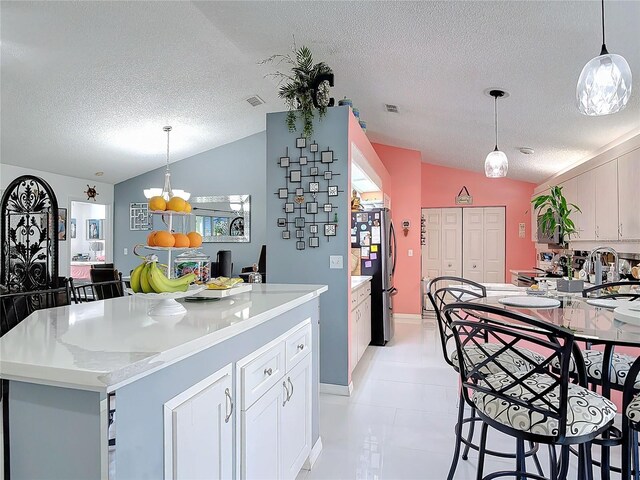 kitchen featuring lofted ceiling, pendant lighting, and stainless steel fridge