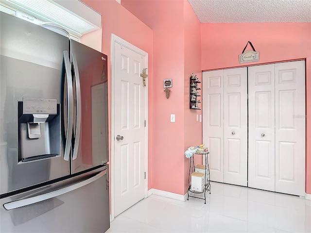 kitchen with stainless steel fridge with ice dispenser, a textured ceiling, and light tile patterned flooring