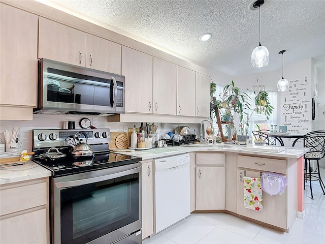 kitchen featuring sink, decorative light fixtures, a textured ceiling, and appliances with stainless steel finishes