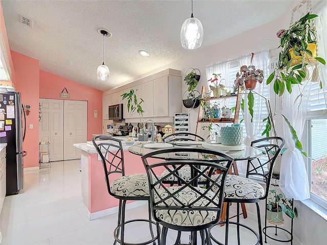 kitchen featuring lofted ceiling, white cabinetry, hanging light fixtures, stainless steel appliances, and a textured ceiling