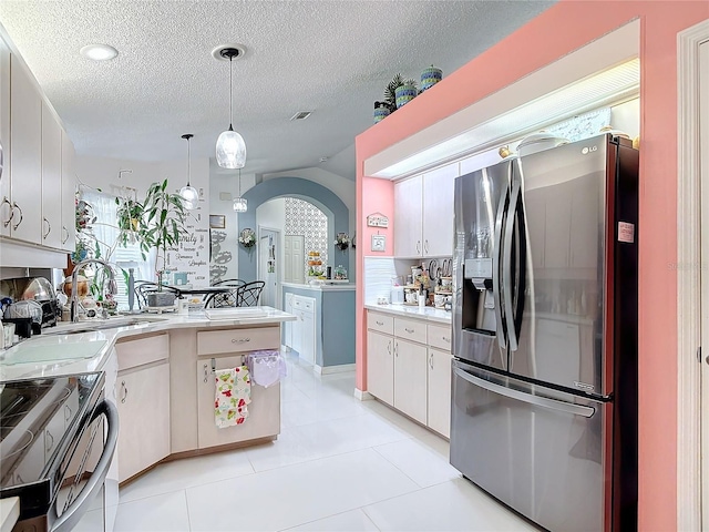 kitchen featuring lofted ceiling, white cabinetry, decorative light fixtures, a textured ceiling, and appliances with stainless steel finishes