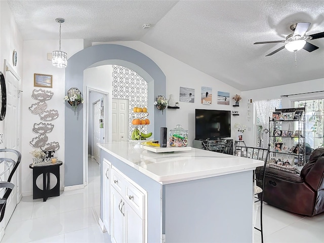 kitchen featuring white cabinetry, decorative light fixtures, a center island, vaulted ceiling, and a textured ceiling