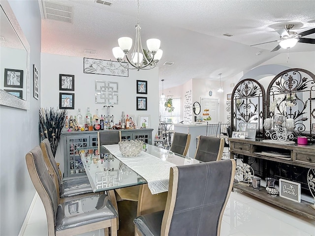 dining area featuring light tile patterned floors, ceiling fan with notable chandelier, vaulted ceiling, and a textured ceiling