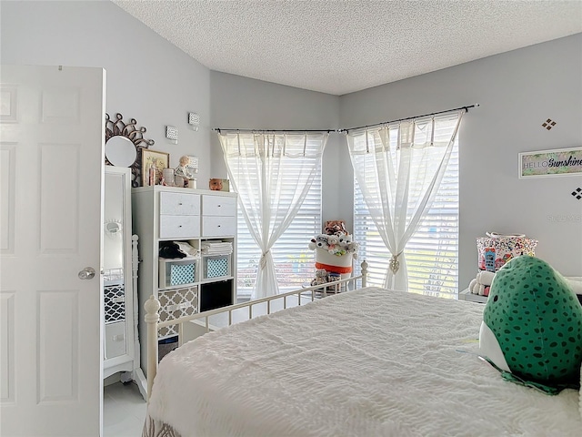 bedroom with tile patterned flooring, vaulted ceiling, and a textured ceiling